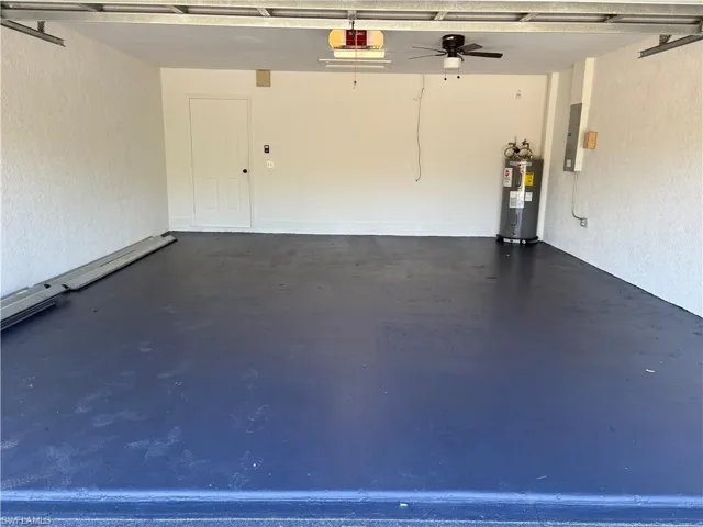 Garage featuring a garage door opener and electric water heater