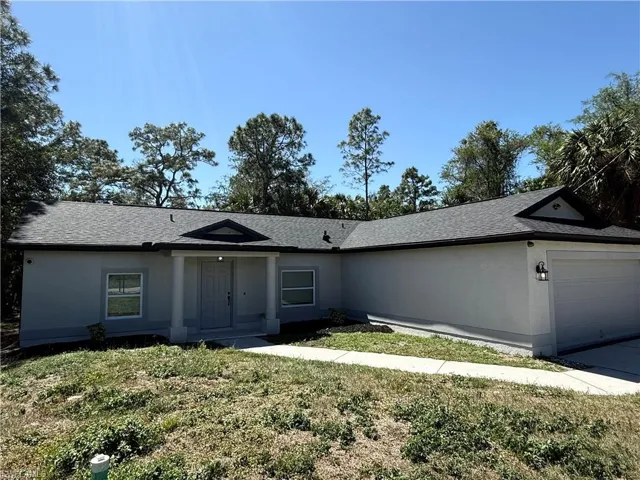 Ranch-style house featuring stucco siding, driveway, a front yard, a shingled roof, and a garage