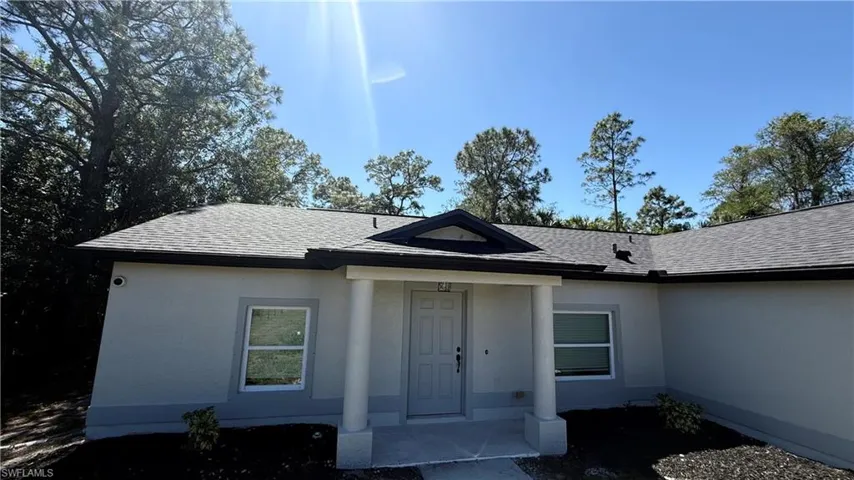 View of exterior entry featuring stucco siding and a shingled roof