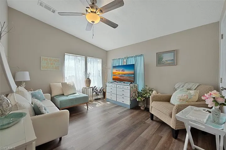 Living room featuring lofted ceiling, wood finished floors, and ceiling fan