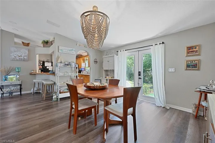 Dining room featuring arched walkways, dark wood-style floors, baseboards, and a chandelier