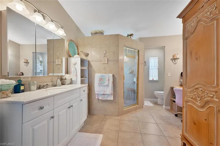 Bathroom with a shower stall, toilet, vanity, and tile patterned flooring