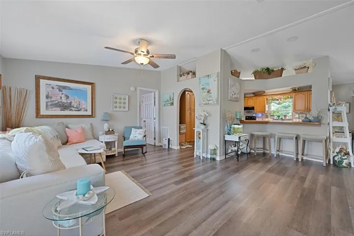 Living area featuring arched walkways, a ceiling fan, wood finished floors, and lofted ceiling