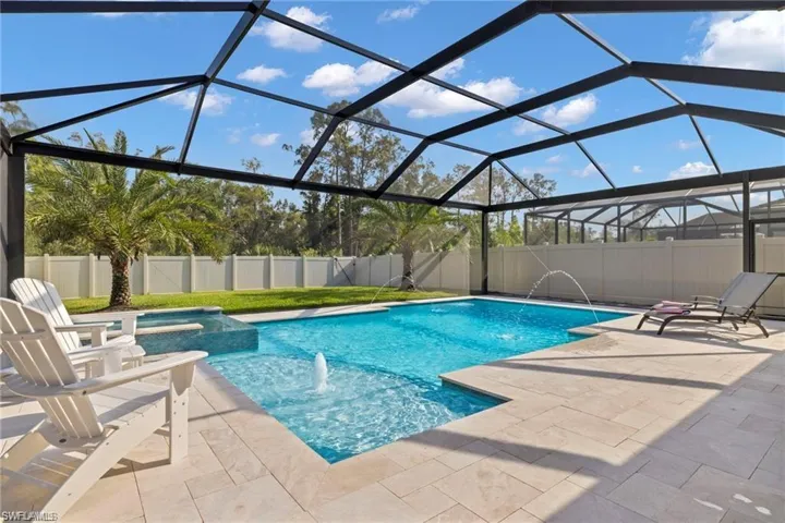 View of pool with glass enclosure, pool water feature, and a patio area