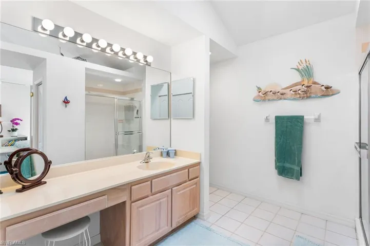 The second-floor primary bathroom has a large, tiled walk-in shower and extra-wide vanity, plus vaulted ceiling with a skylight.