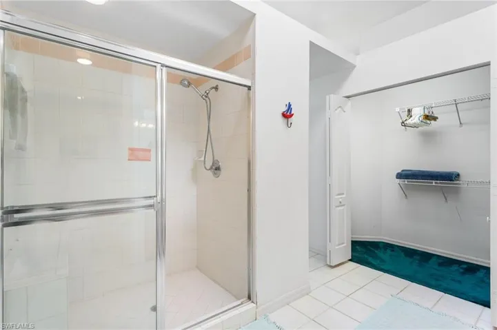 The second-floor primary bathroom has a large, tiled walk-in shower and extra-wide vanity, plus vaulted ceiling with a skylight.