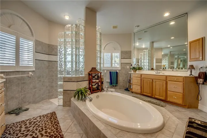 Bathroom with vanity, walk in shower, a garden tub, light tile patterned floors, and recessed lighting