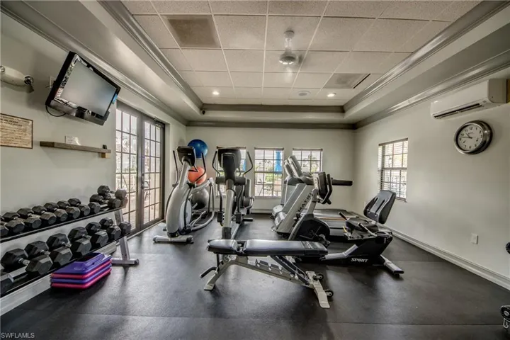 Exercise room with ornamental molding, a drop ceiling, and a raised ceiling