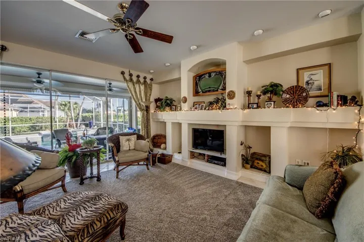 Living room with a sunroom, ceiling fan, and a glass covered fireplace