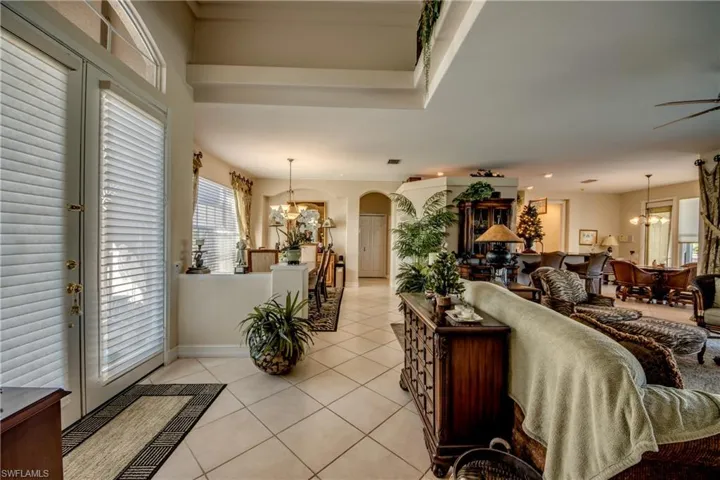 Living room with suspended lighting, arched walkways, healthy amount of natural light, and light tile patterned floors