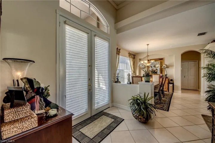 Entrance foyer featuring french doors, arched walkways, light tile patterned floors, and suspended lighting