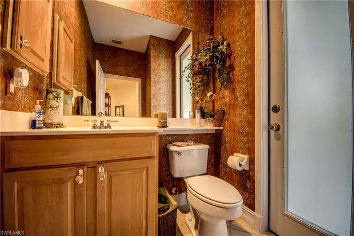 Half bathroom featuring vanity and wallpapered walls
