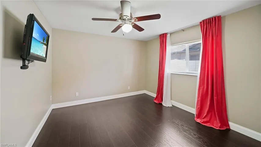 Bedroom featuring ceiling fan, dark wood-look laminate flooring, and TV