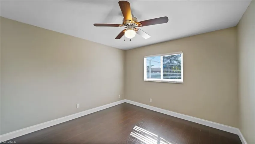 Bedroom with ceiling fan and dark wood-look laminate flooring