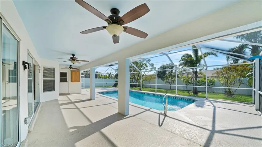 View of heated swimming pool screened under-truss lanai area with three ceiling fans