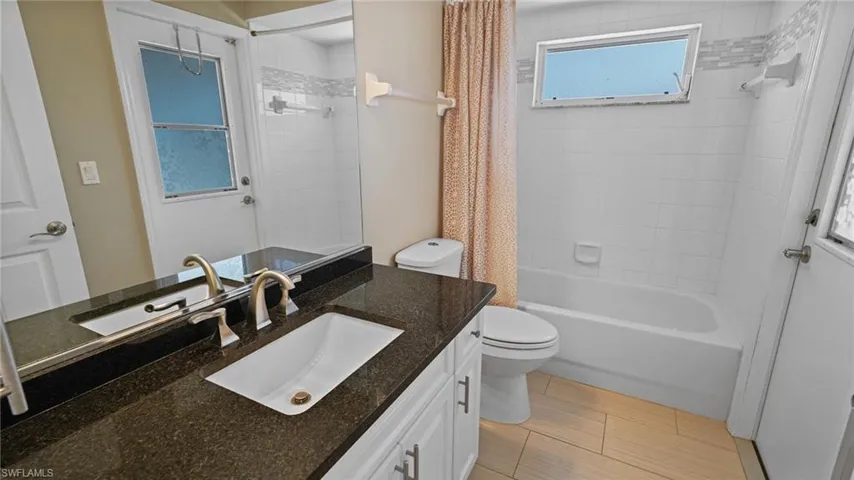 Full pool bathroom featuring shower / bath combination with curtain and vanity with granite counter