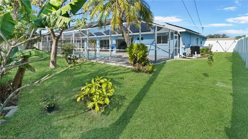 Fenced back yard facing the pool with exotic tropical plants & trees