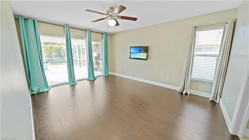 Primary bedrooms with triple sliders to pool deck, dark wood-look laminate flooring, ceiling fan and TV
