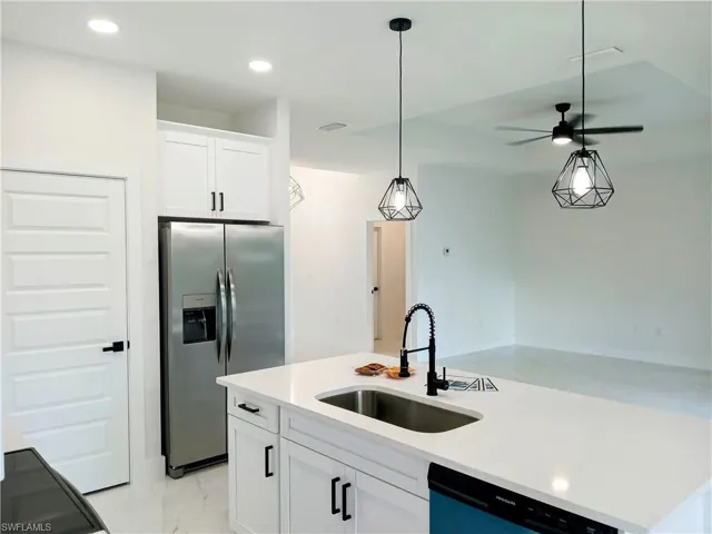 Kitchen with dishwasher, an island with sink, ceiling fan, stainless steel fridge, and sink