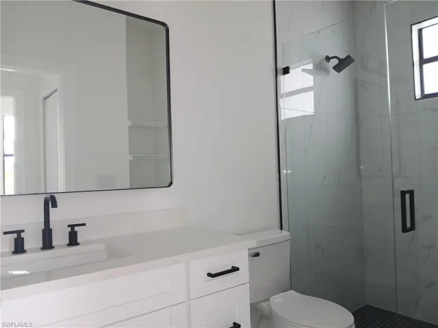 Bathroom featuring a wealth of natural light, vanity, walk in shower, and toilet