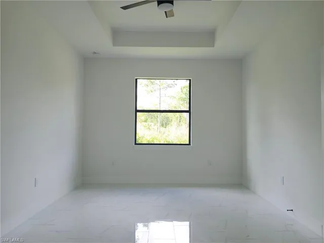 Tiled spare room featuring ceiling fan and a raised ceiling