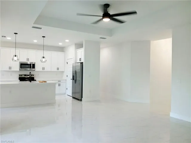 Kitchen featuring ceiling fan, hanging light fixtures, stainless steel appliances, and light tile patterned floors
