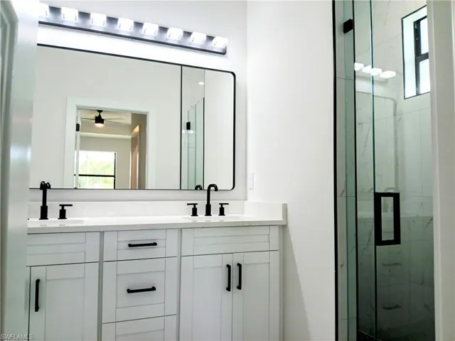 Bathroom with walk in shower, ceiling fan, and double sink vanity
