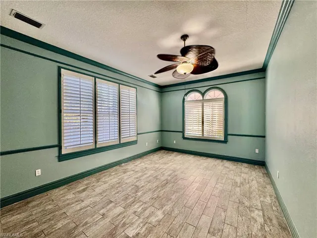 Spare room featuring a textured wall, a textured ceiling, ceiling fan, and wood finished floors