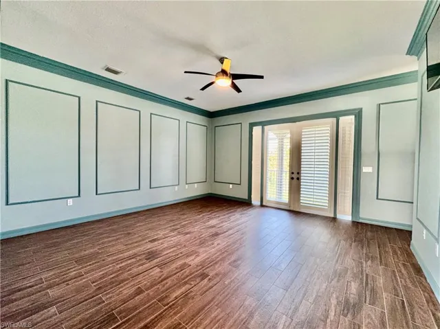 Unfurnished room with crown molding, dark wood-style floors, a ceiling fan, french doors, and a textured ceiling