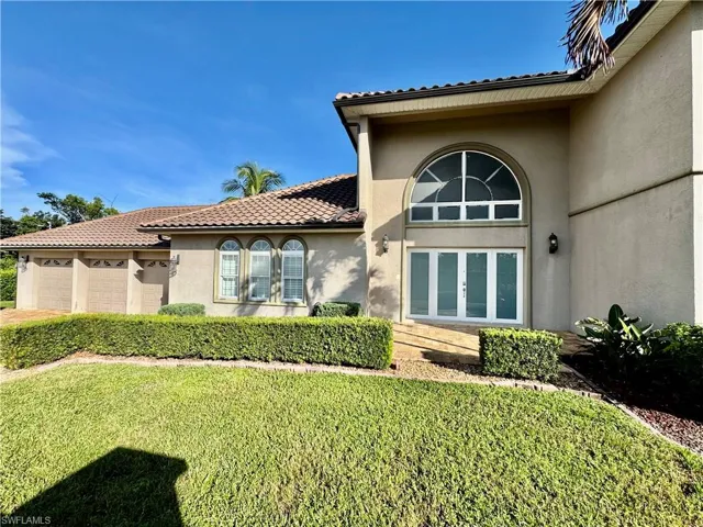 Property entrance featuring stucco siding, an attached garage, a lawn, and a tile roof