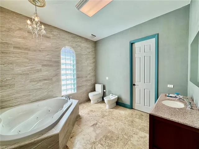Full bathroom featuring a tub with jets, vanity, a bidet, and a chandelier