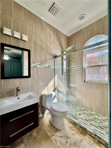 Bathroom with a stall shower, tile walls, vanity, crown molding, and tile patterned flooring
