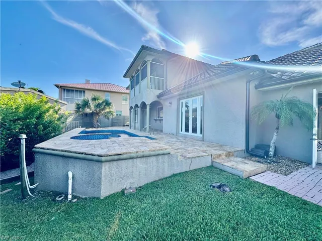 Rear view of house featuring an outdoor hot tub, stucco siding, a patio area, a balcony, and french doors