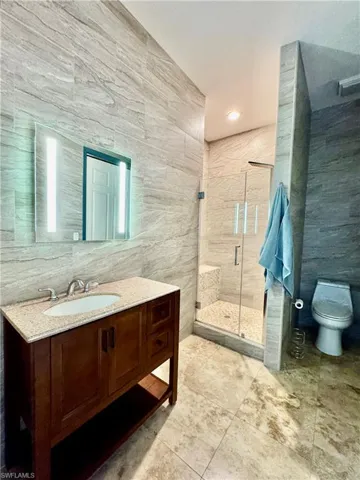 Bathroom with tile walls, vanity, a stall shower, and tile patterned floors