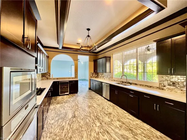 Kitchen featuring backsplash, a raised ceiling, light countertops, and ornamental molding