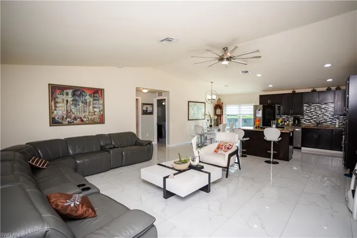 Open-concept living space featuring high ceilings, white tile flooring, recessed lighting, and a modern ceiling fan