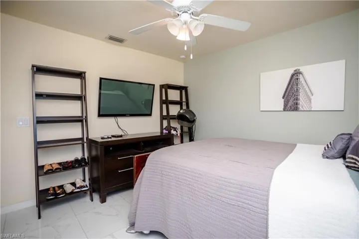 Spacious room featuring large format tile flooring, a ceiling fan with integrated lighting, and a wall-mounted flat-screen television