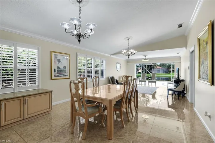 Vaulted ceiling with crown molding, polished tile flooring, built-in cabinetry with a stone countertop, and plantation shutters