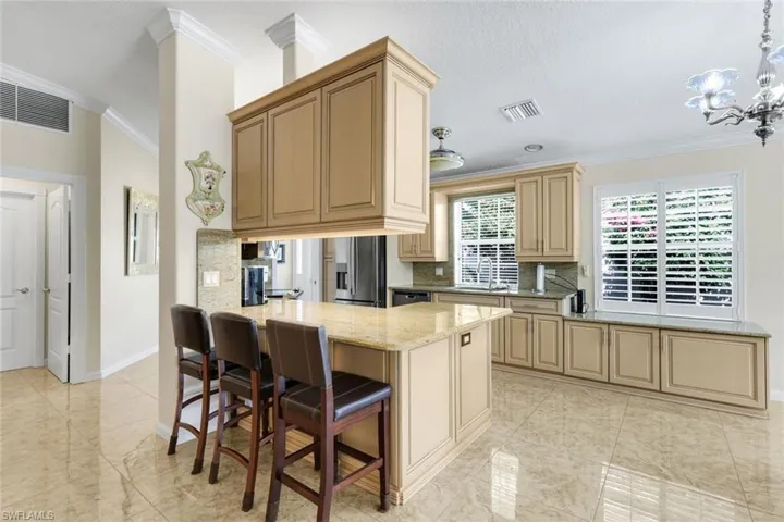 Kitchen featuring light-toned cabinetry, a built-in island with countertop seating, light-toned stone countertops, and tiled flooring