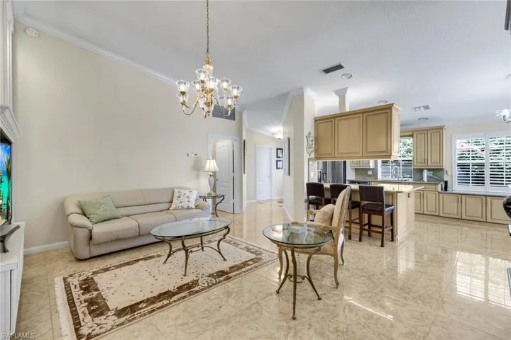Tiled flooring throughout, high vaulted ceiling, crown molding, kitchen with light wood-finish cabinetry, and built-in plantation shutters