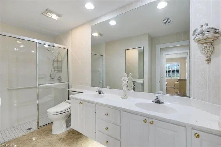 Dual vanity with integrated sinks, full-width mirror, white cabinetry, and gold-tone hardware