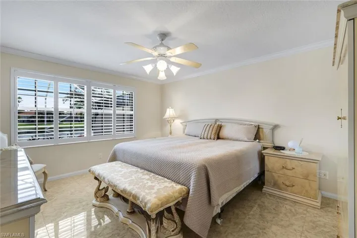 Room featuring large windows with white plantation shutters, crown molding, a ceiling fan with integrated lighting, and tile flooring