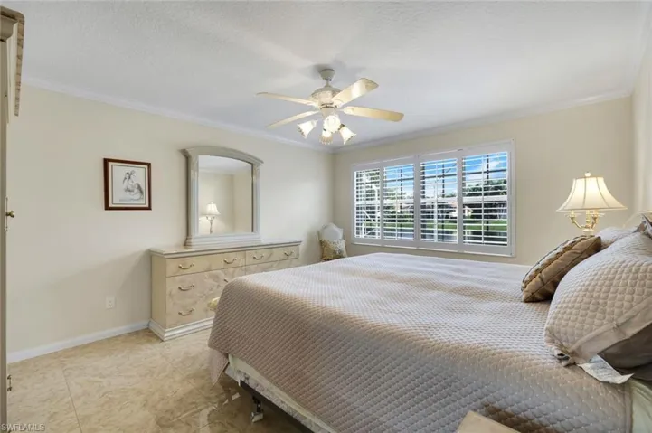 Expansive window with plantation shutters, ceiling fan with light fixture, crown molding, and tiled flooring
