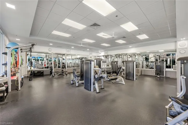 Fitness center featuring extensive exercise equipment, mirrored walls, recessed lighting, and a suspended ceiling with integrated ceiling fans