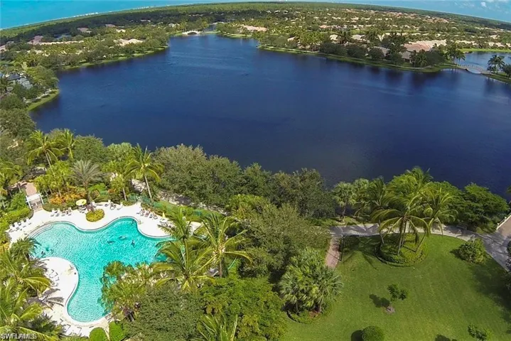 Lush landscaping surrounding a freeform swimming pool and expansive body of water