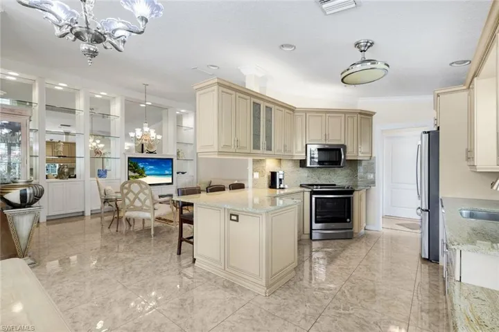 Kitchen featuring a central island, light-toned cabinetry, stainless steel appliances, and polished tile flooring