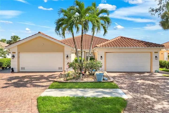 Mediterranean-style residence featuring a tile roof, stucco exterior, dual garage doors, and a paver driveway