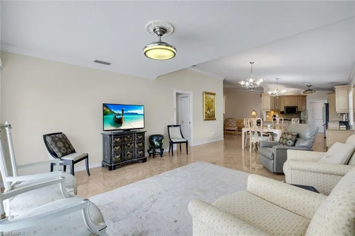 Open-concept living space featuring high ceilings, crown molding, tile flooring, recessed lighting, and a ceiling fan with light fixture