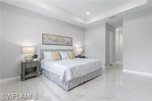 Bedroom featuring a raised ceiling and light tile floors
