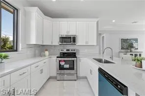 Kitchen featuring white cabinets, light tile flooring, stainless steel appliances, tasteful backsplash, and sink
